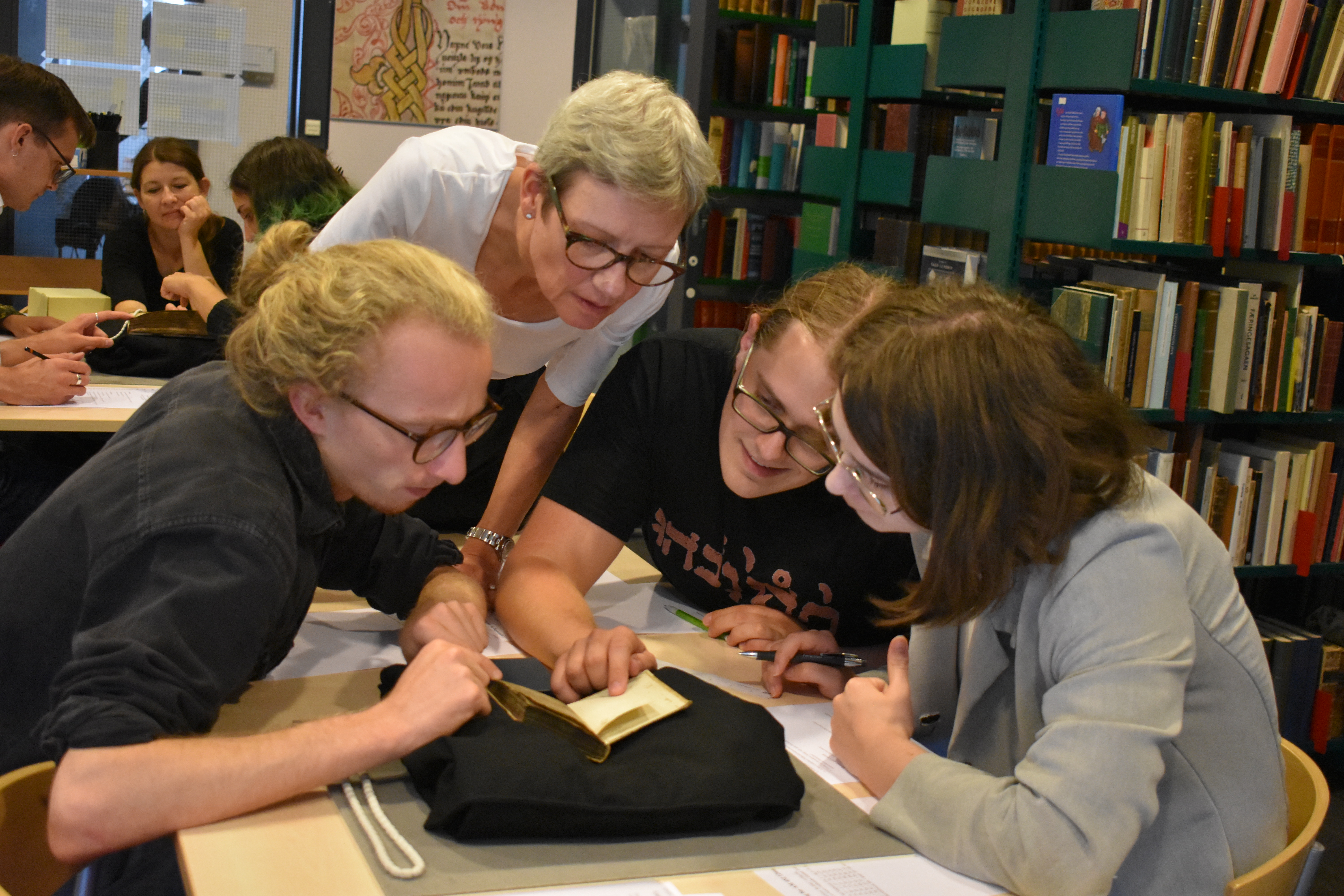 Students and a teacher study a manuscript