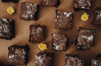 Horft ofan á ferkantaða brúnkubita (brownies). Inn á milli þeirra eru þrír gulir fíflar.