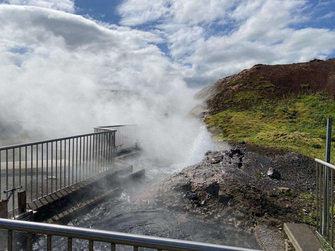 Mikil gufa stígur upp af goshver sem er girtur af með rammgerðri girðingu.