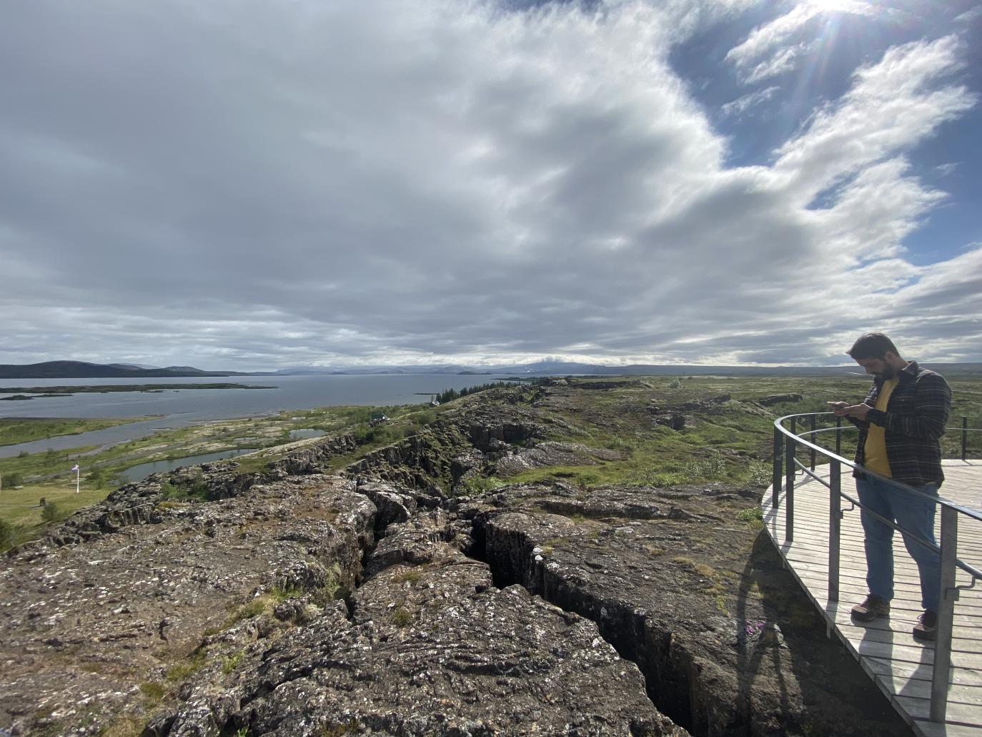 Maður stendur á útsýnispalli og horfir yfir gamla sprungu.